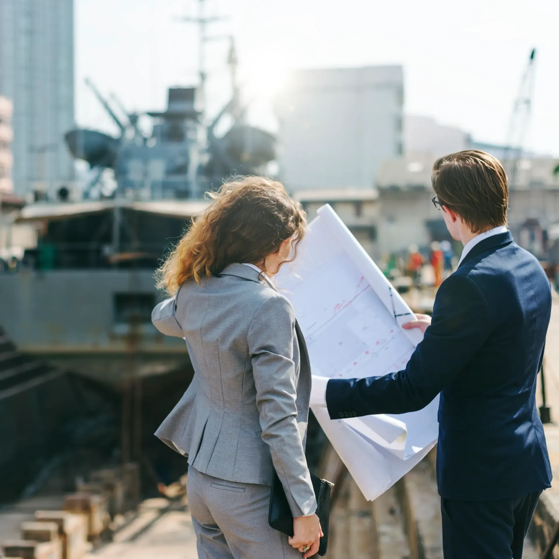 A man and a woman are looking at a blueprint.