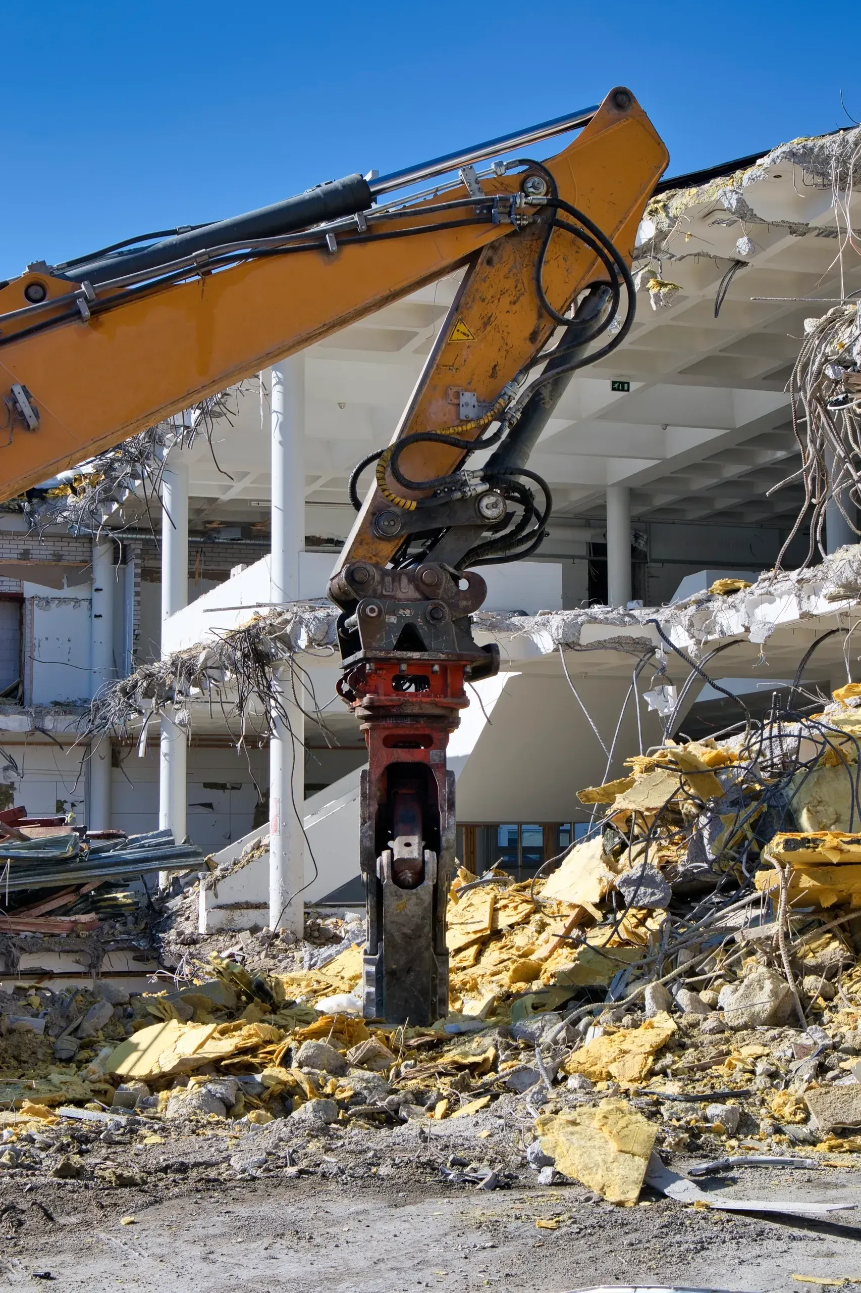 A large building is being demolished by a large excavator.