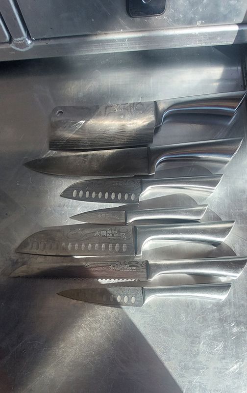 A Row of Knives Sitting on Top of a Stainless Steel Counter — Shaving Sharp Knives And Tools in Warwick, QLD