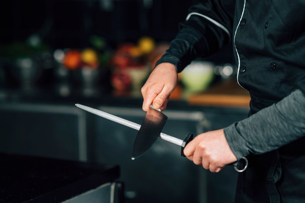 A Man in Chef's Uniform is Sharpening a Knife — Shaving Sharp Knives And Tools in Gatton, QLD