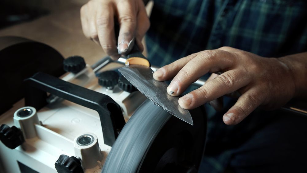 A Kitchen Knife Is Being Sharpened on a Grinding Wheel — Shaving Sharp Knives And Tools in Gatton, QLD