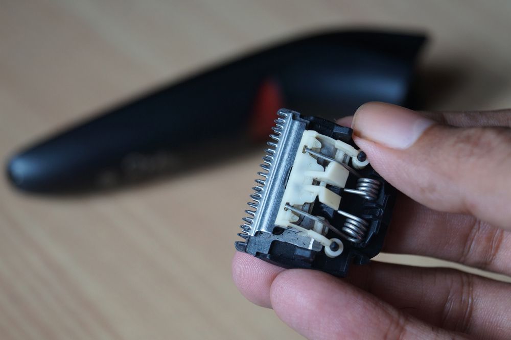 A Person Is Holding A Hair Clipper Blade In Their Hand — Shaving Sharp Knives And Tools in Centenary Heights, QLD