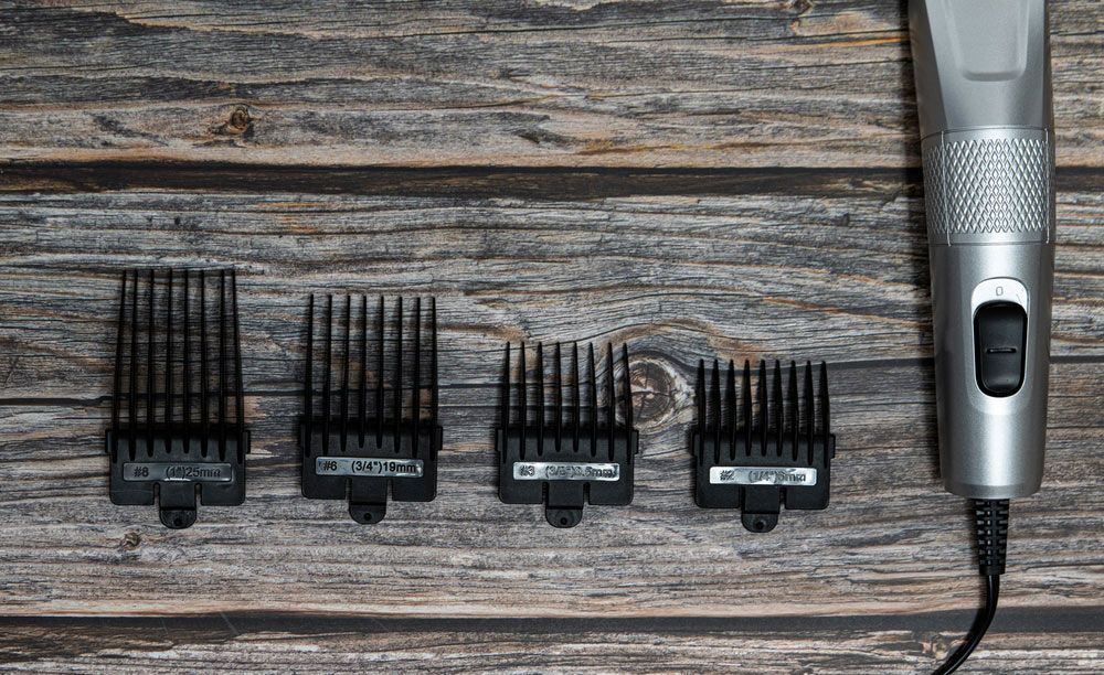 A Hair Clipper With Four Combs On A Wooden Table — Shaving Sharp Knives And Tools in Warwick, QLD