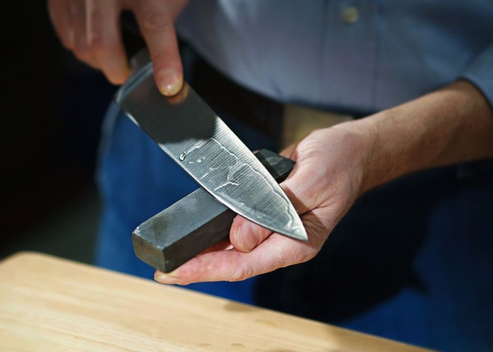A Man Sharpening a Knife With a Whetstone — Shaving Sharp Knives And Tools in Toowoomba, QLD