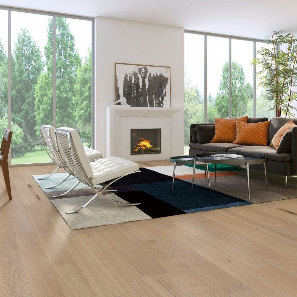 Living room with large windows overlooking trees, fireplace, and modern furniture.