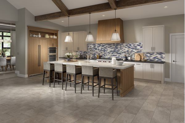 Modern kitchen with large island and breakfast bar, light wood cabinets, and patterned backsplash.