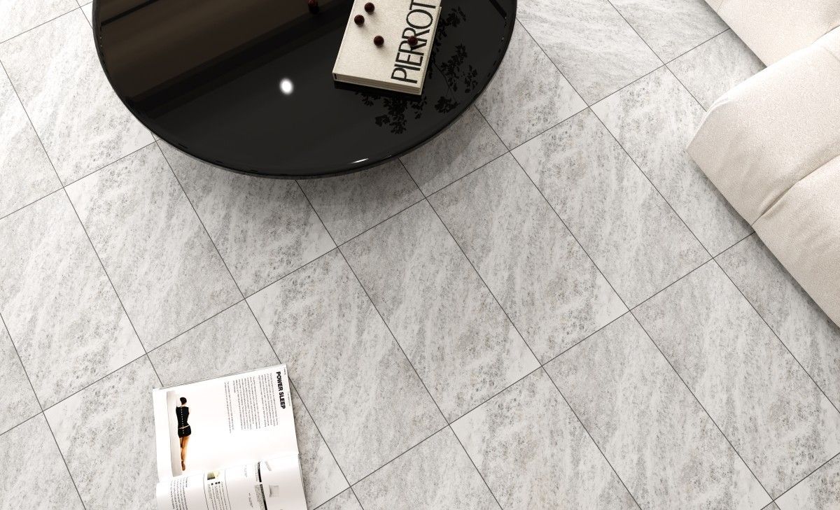 Overhead view of a living room with light gray, diamond-patterned tile floor, black coffee table, and off-white sofa.