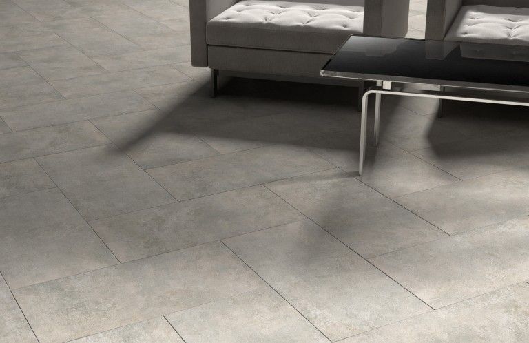 Gray tiled floor with couch and modern table casting a shadow.