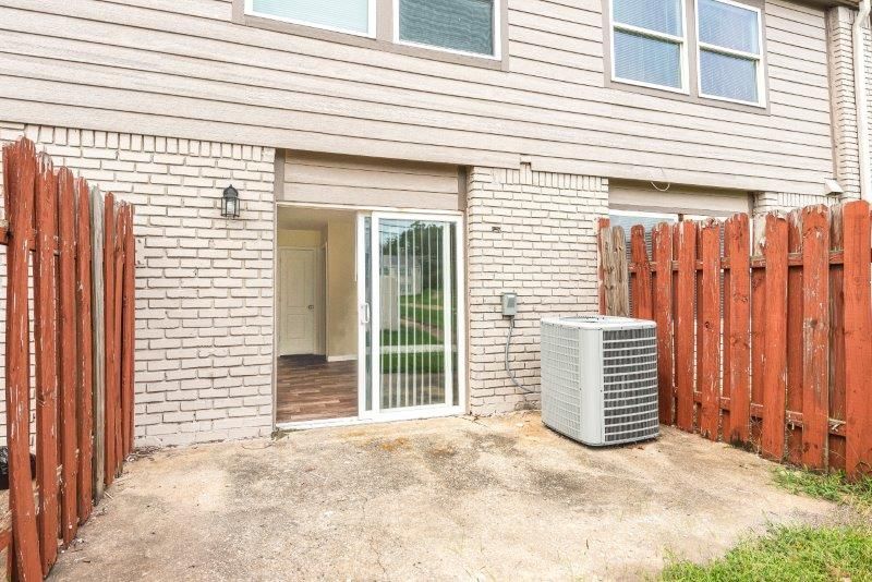 The backyard of a house with a sliding glass door and an air conditioner.