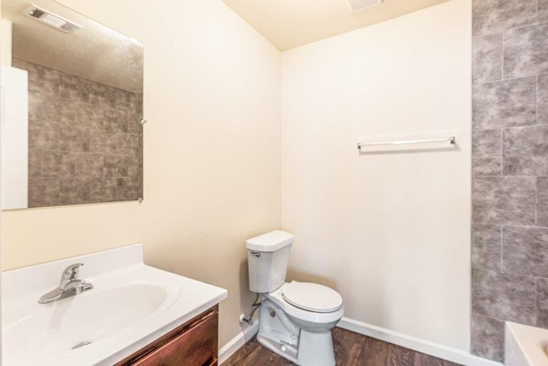 A bathroom with a toilet , sink and mirror.