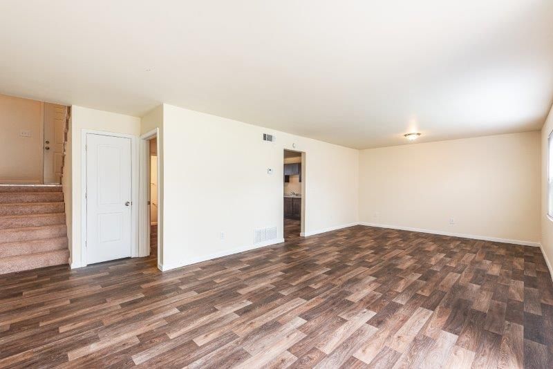 An empty living room with hardwood floors and white walls.