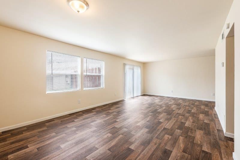 An empty living room with hardwood floors and sliding glass doors.