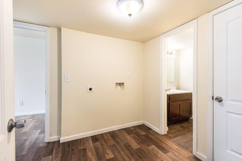 An empty room with hardwood floors and a washer and dryer.