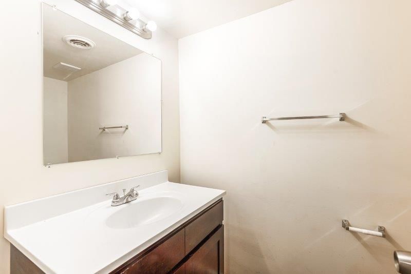 A bathroom with a sink , mirror and towel rack.