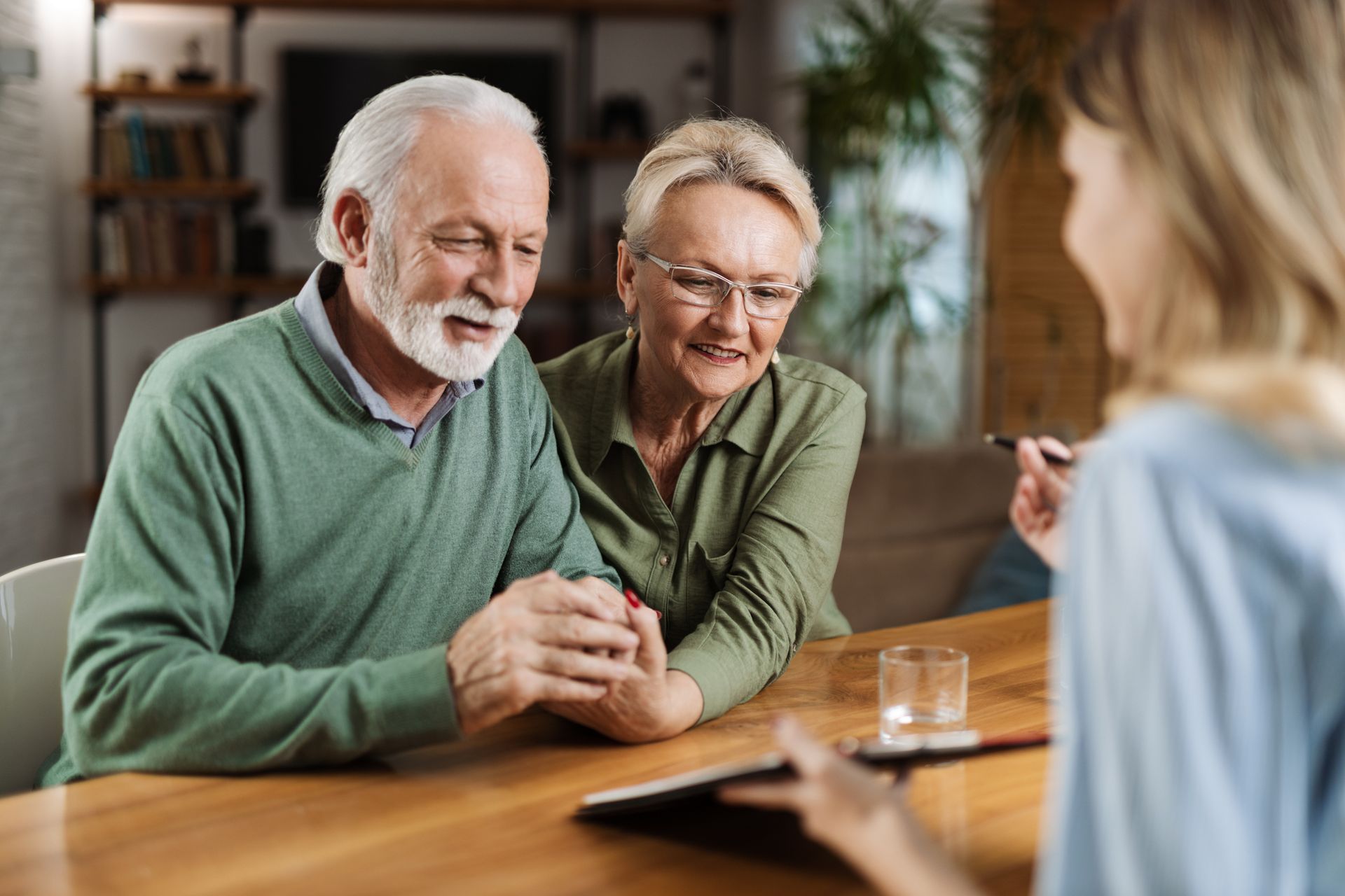 Elderly couple consults with a professional at a table, discussing paperwork, indoors.