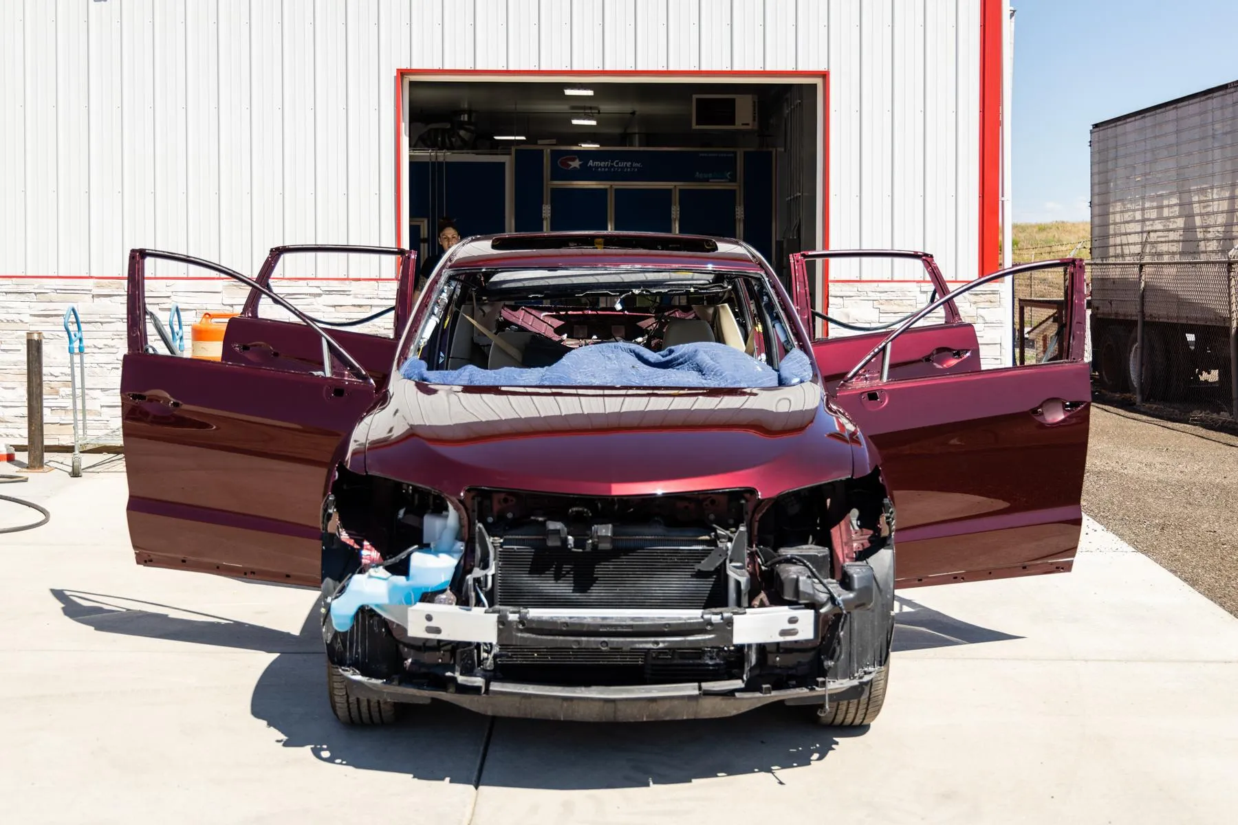 A red car with its doors open is parked in front of a building.