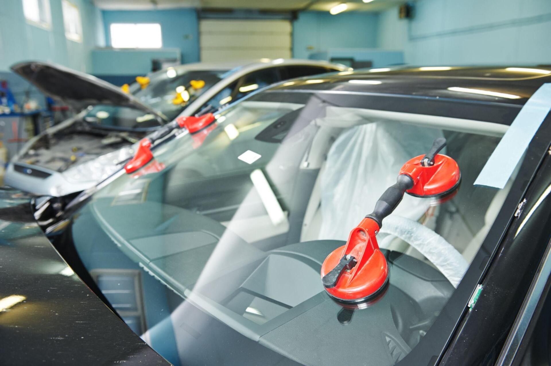 A car windshield is being replaced in a garage.