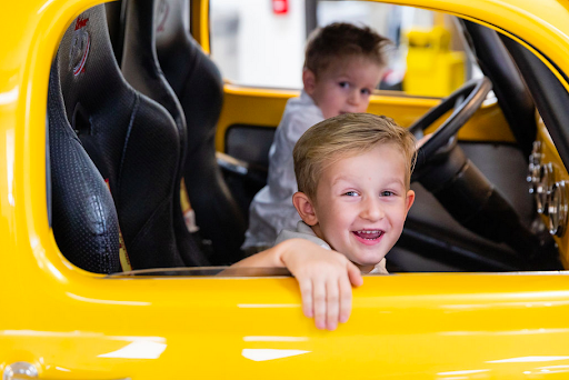 Two young boys are sitting in a yellow car looking out the window.