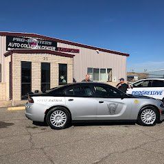 A silver car is parked in front of a building.