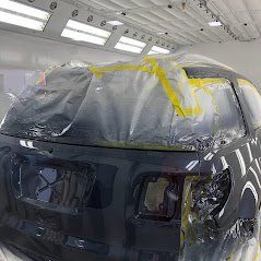 A car is covered in plastic wrap in a paint booth.