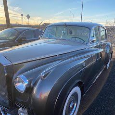 A black car with white tires is parked on the side of the road.