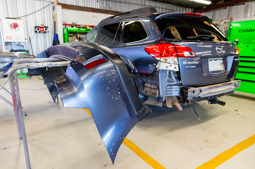 A blue subaru outback is being repaired in a garage.
