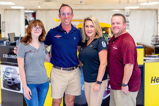 A group of people are posing for a picture in a car dealership.