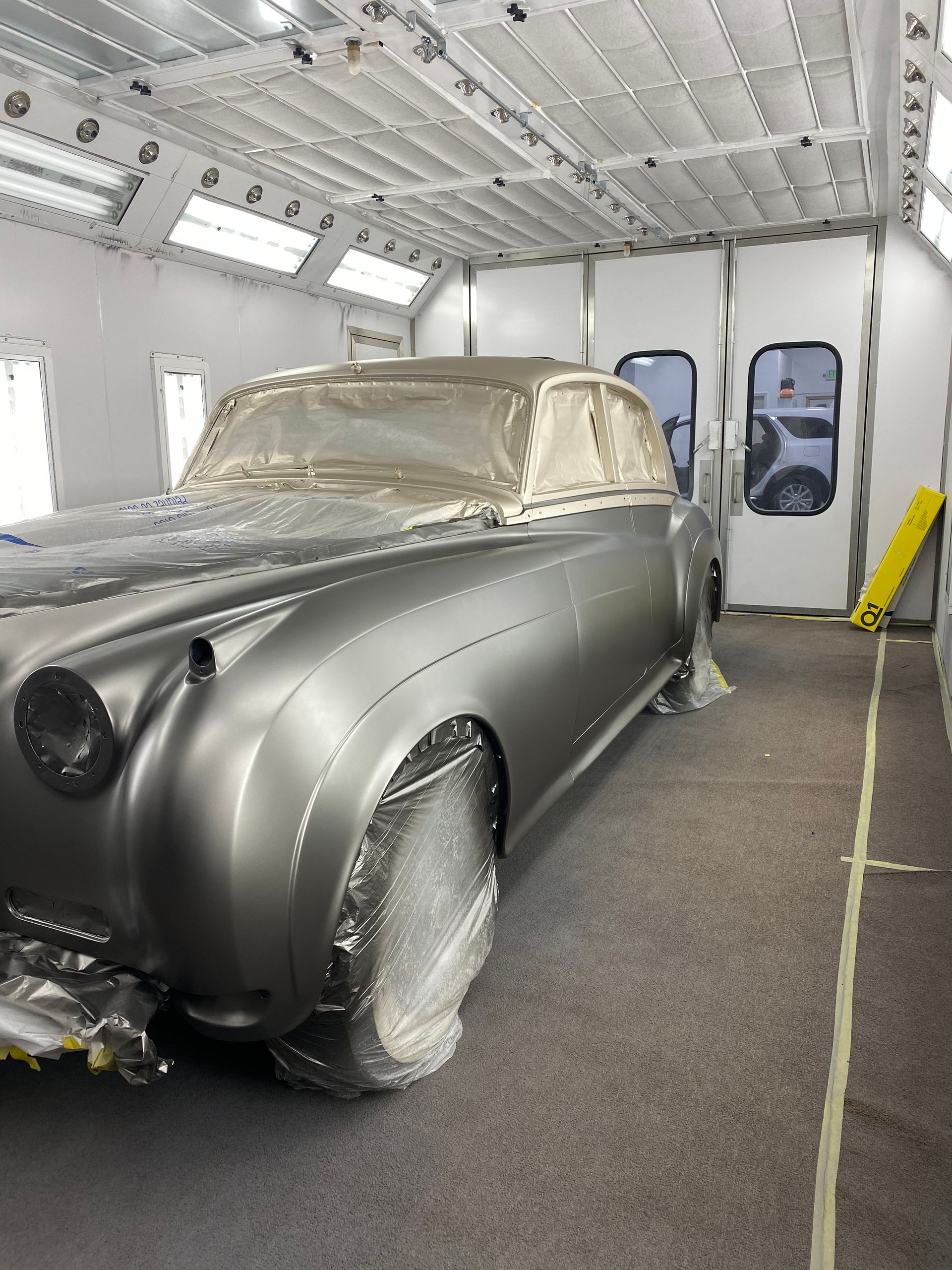 A car is wrapped in plastic in a paint booth