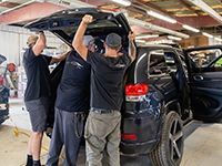 A group of men are working on a car in a garage.