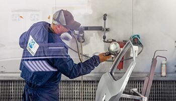 A man is painting a car door in a garage.