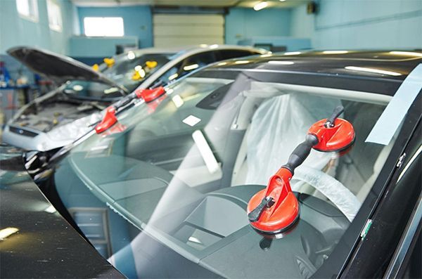 A car windshield is being replaced in a garage.