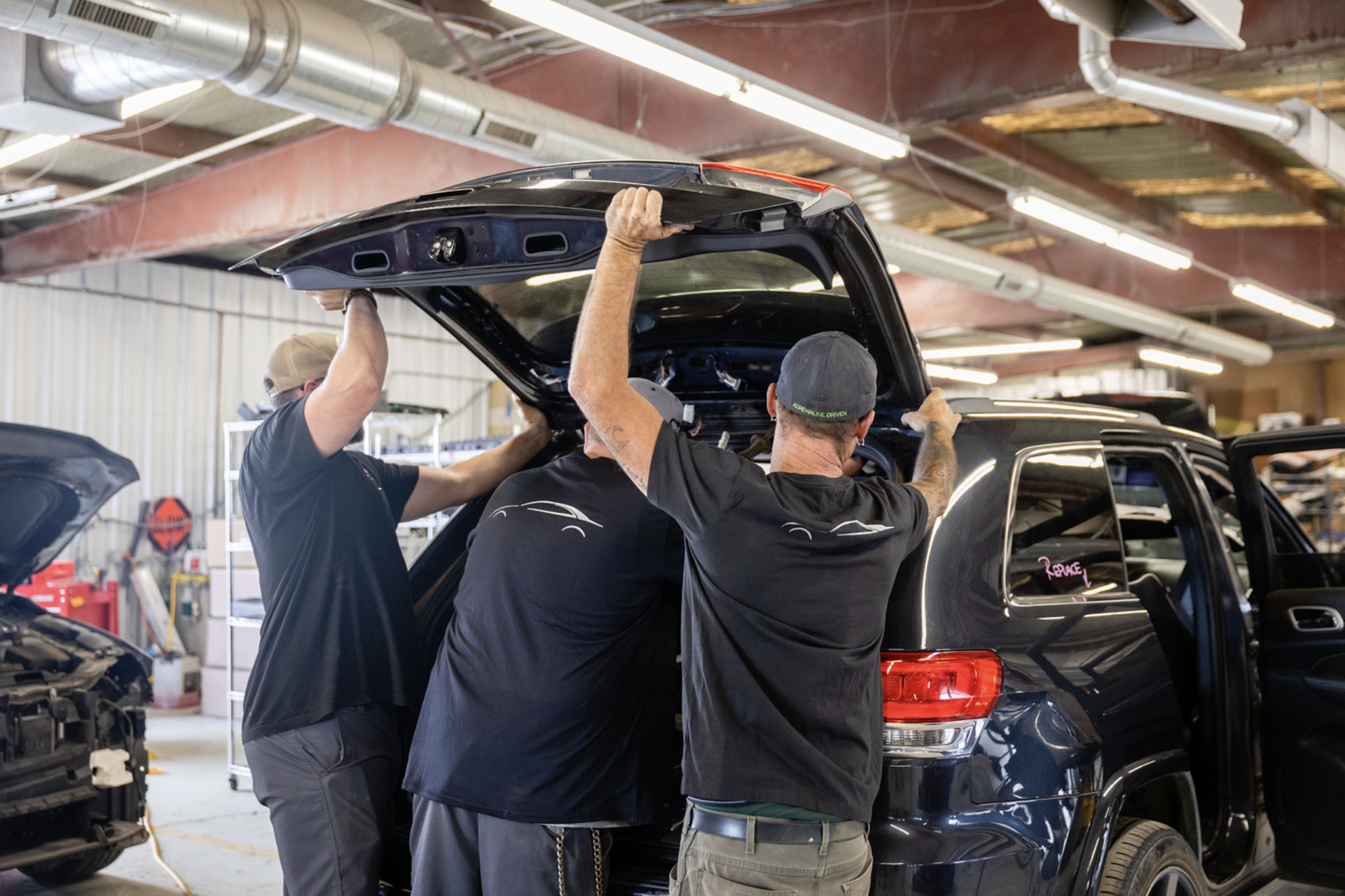 A group of men are working on a car in a garage.