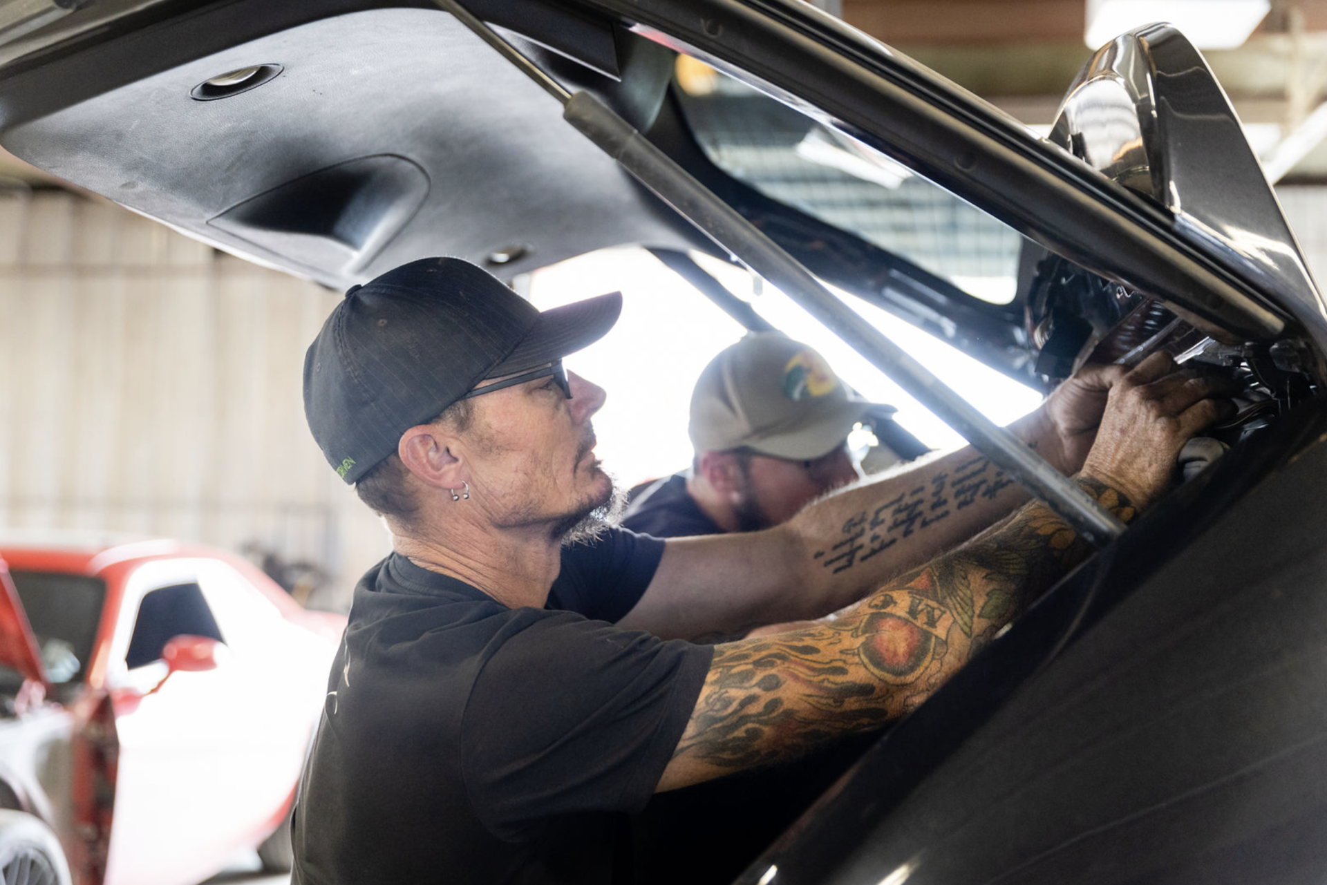 Two men are working on a car in a garage.