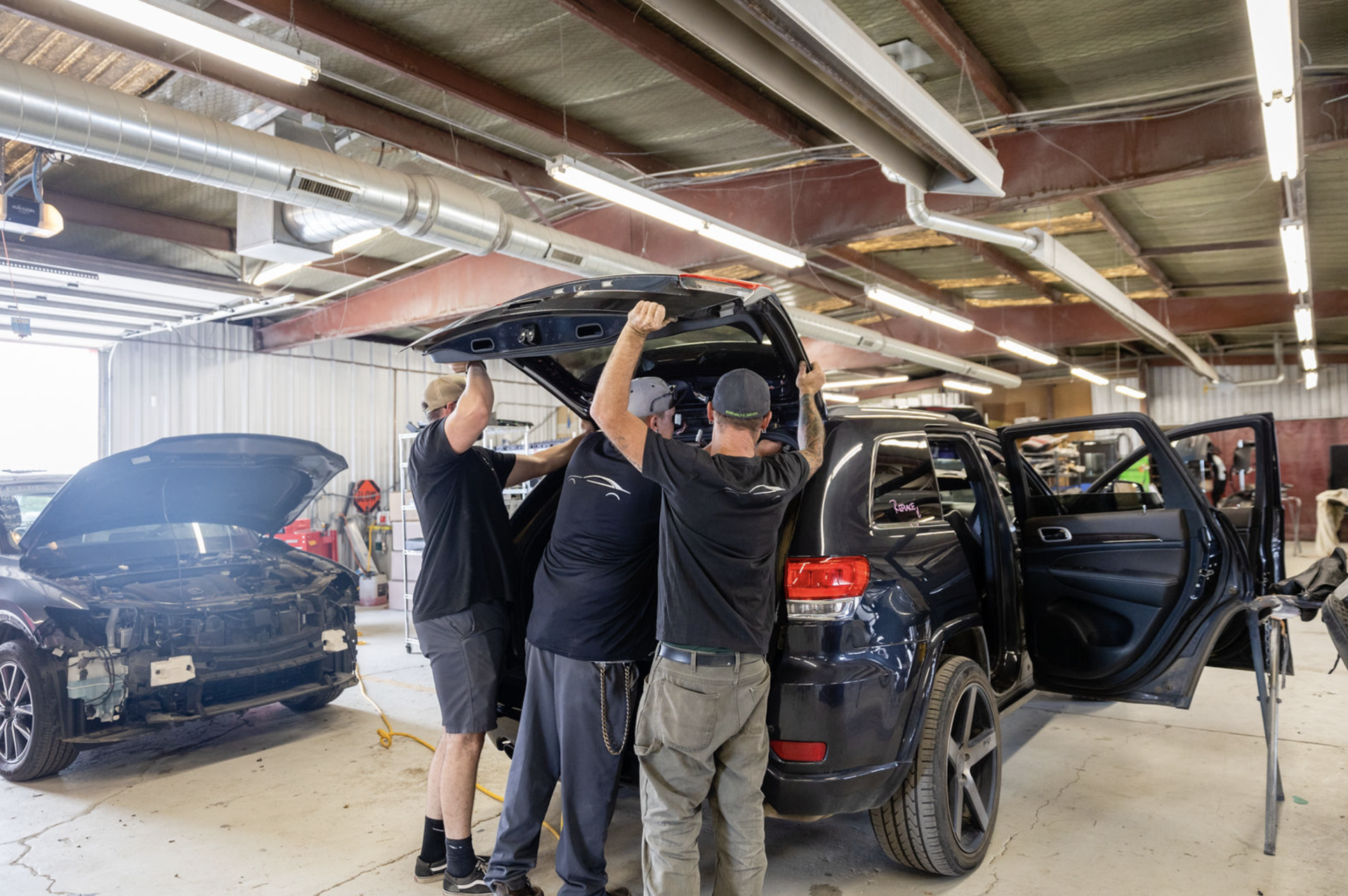 A group of men are working on a car in a garage.