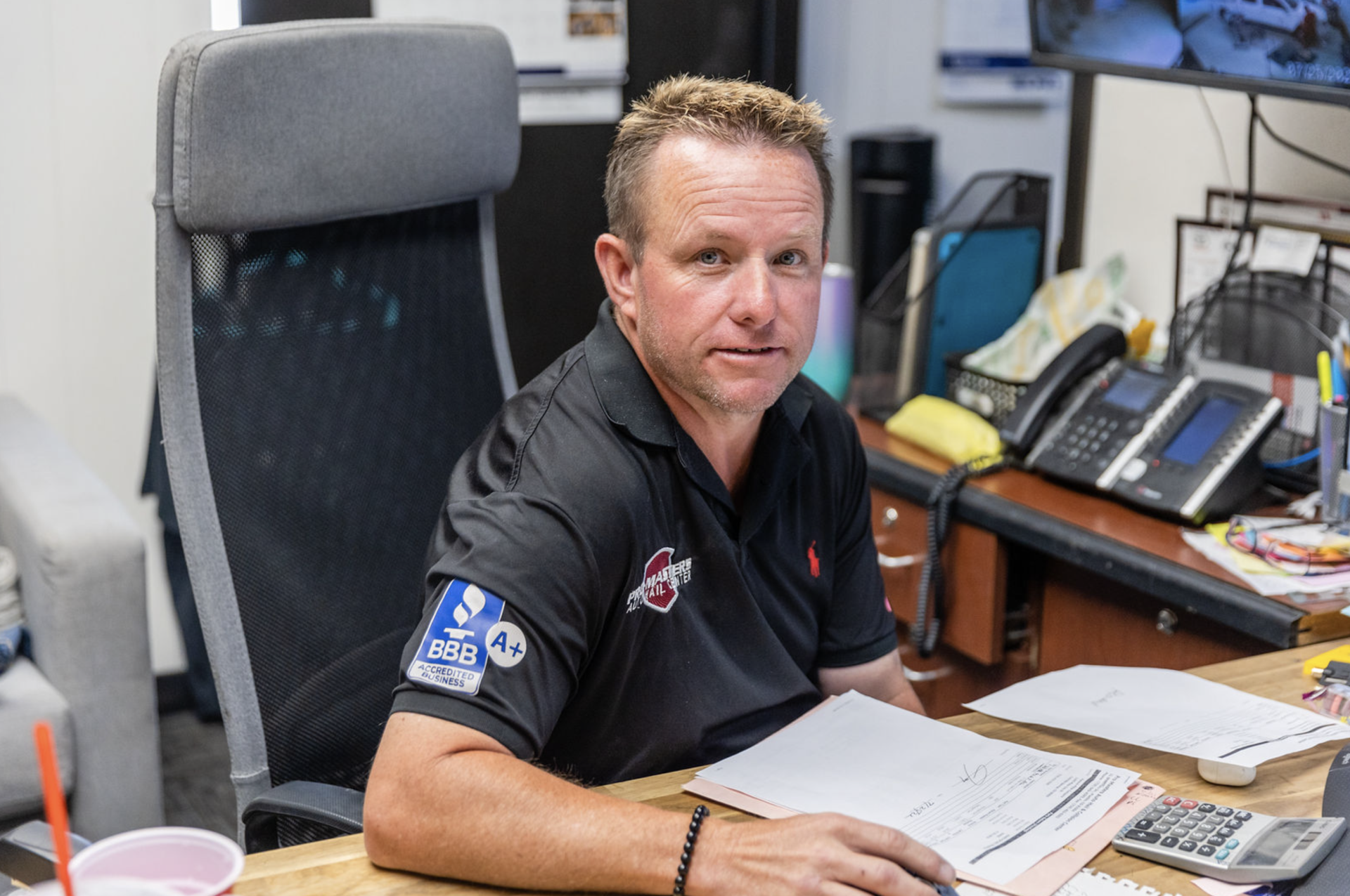 A man is sitting at a desk in an office looking at the camera.