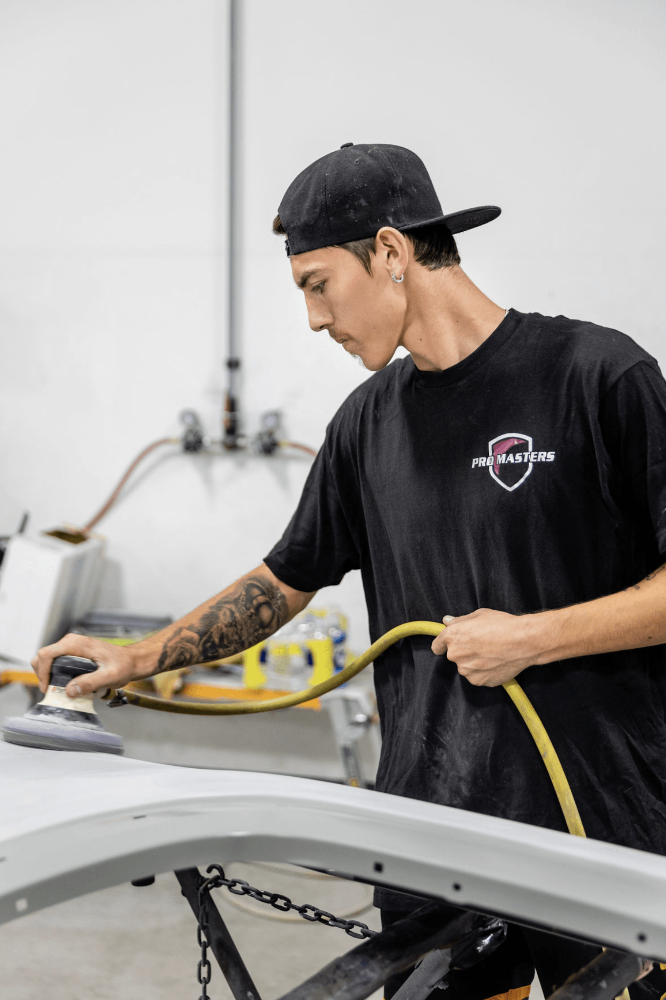 A man is using a hose to sand a piece of metal.