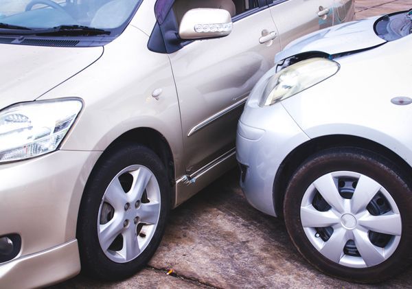 Two cars are parked next to each other and one has a damaged headlight.
