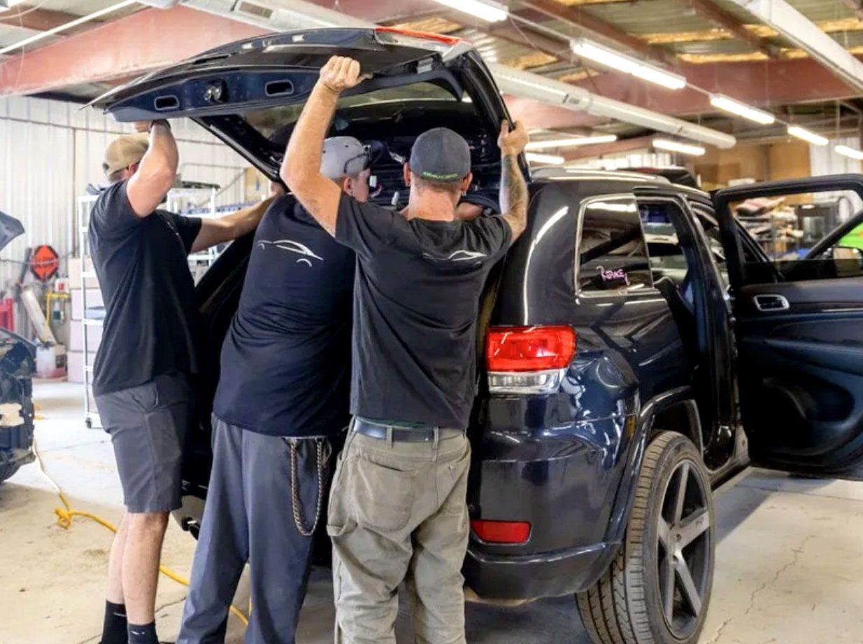 A group of men are working on a car in a garage.