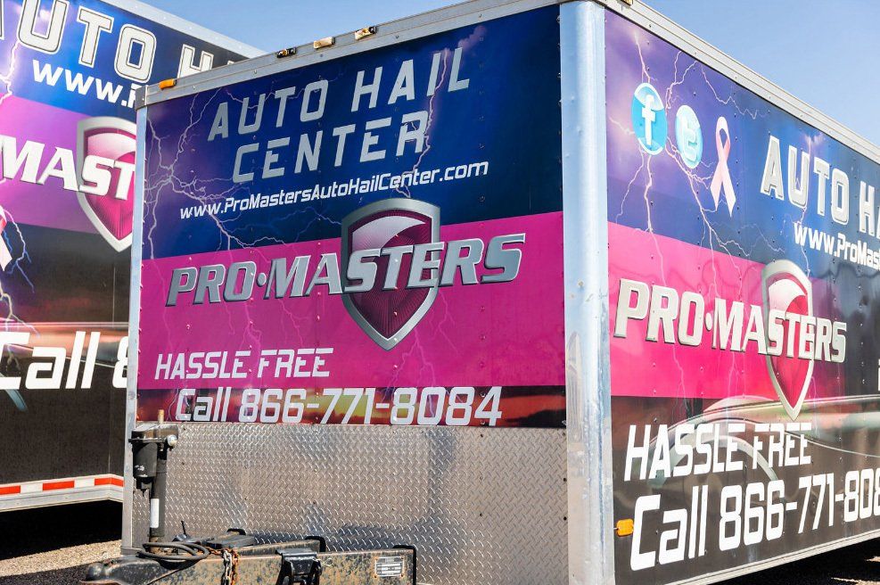 Two trailers with advertisements for auto hail center pro masters