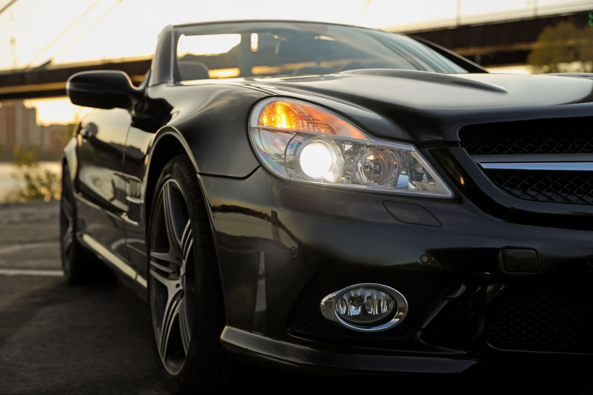 A black sports car is parked in front of a bridge.