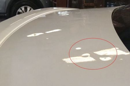White car roof with water droplets in the sunlight, circled in red.