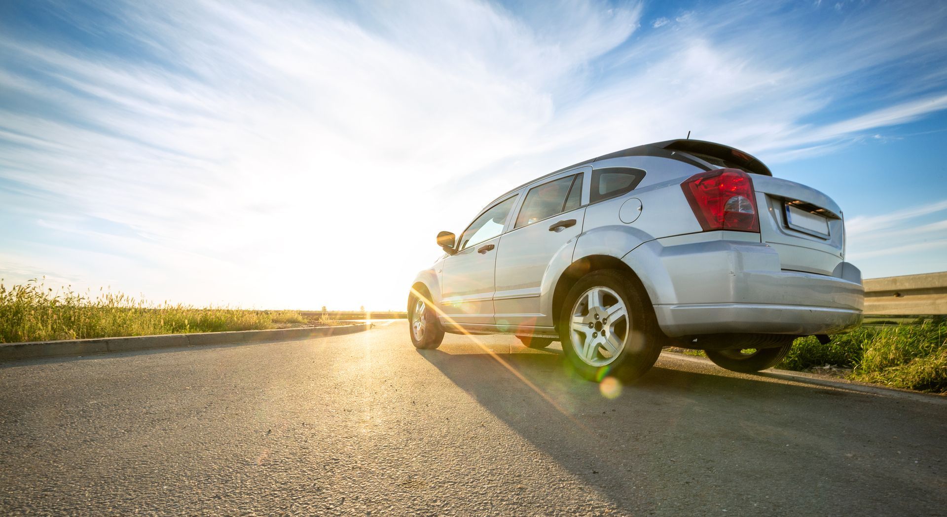 A white car is parked on the side of a road.