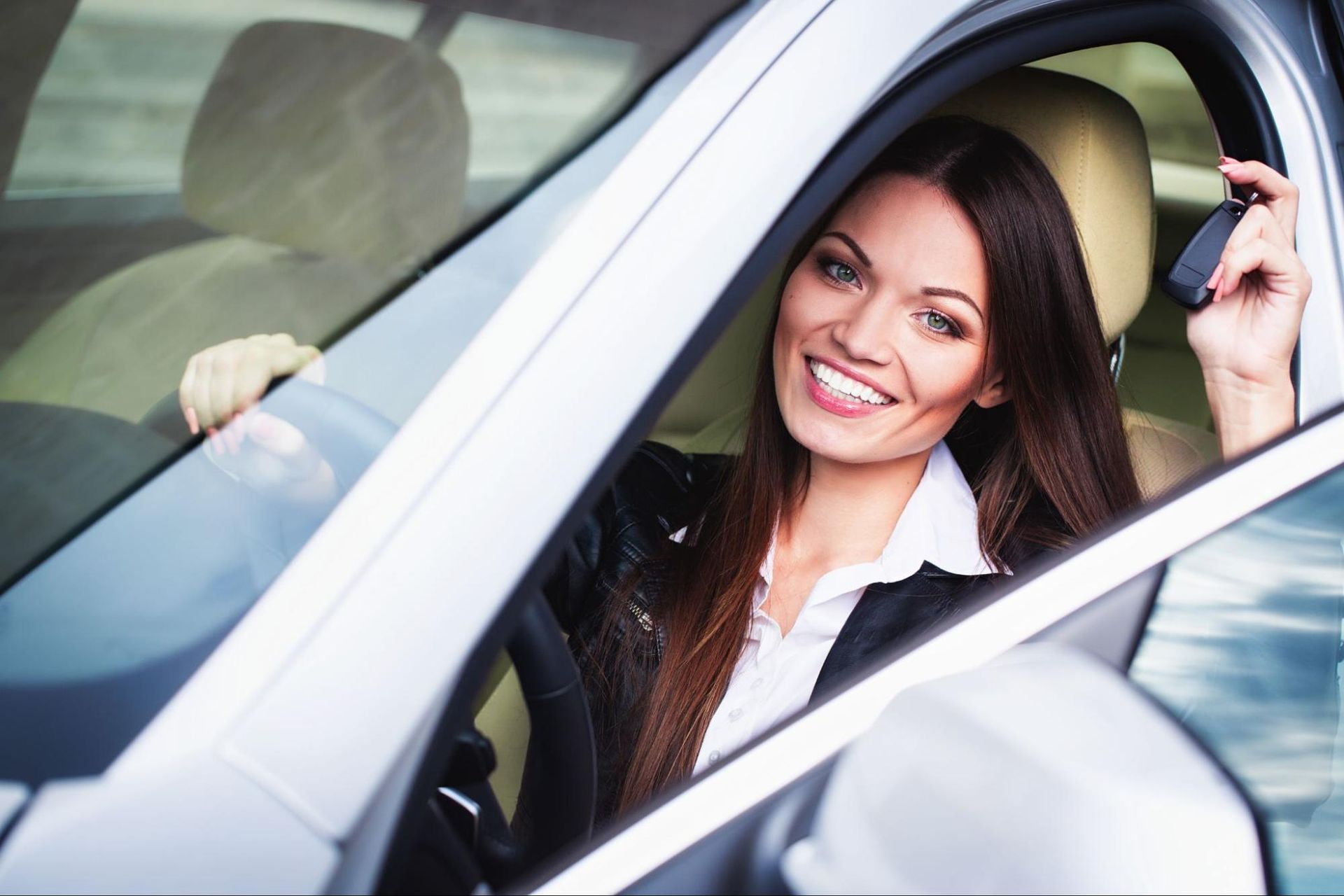 A woman is sitting in a car holding a car key.