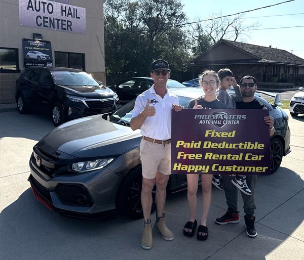People with a car posing with a sign outside an auto hail center. The sign says