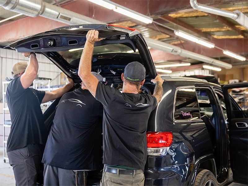 A group of men are working on a car in a garage.
