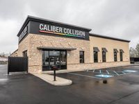 A caliber collision building with a parking lot in front of it.
