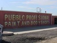 A red building with a sign on it that says `` pueblo professional paint and bodyshops ''.
