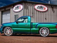 A green truck is parked in front of a building.