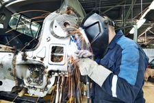 A man is welding a car in a garage.