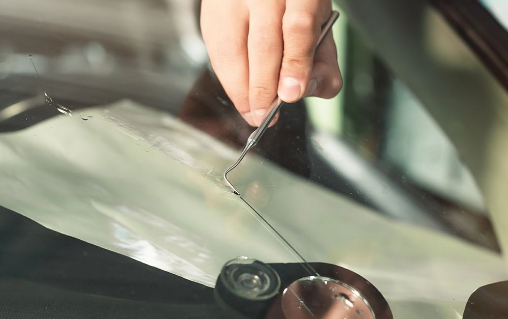 A person is fixing a broken windshield with tweezers.